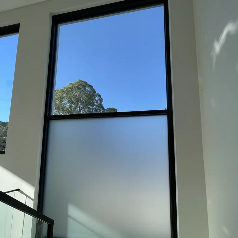 Frosted window film installed on a residential staircase window, providing privacy while allowing natural light to enter the home and maintaining a clean modern appearance.