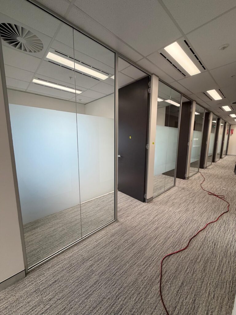 Commercial office glass partitions with frosted privacy film installation