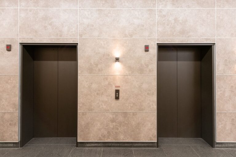 Architectural wall wraps with a stone-look finish installed around commercial elevator surrounds in a Sydney office building