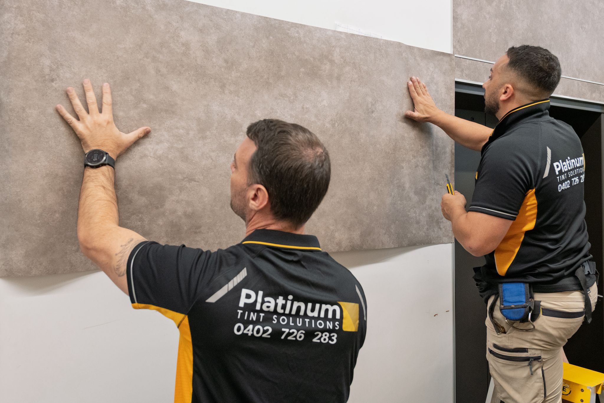 Technicians installing custom architectural wraps on interior wall surfaces