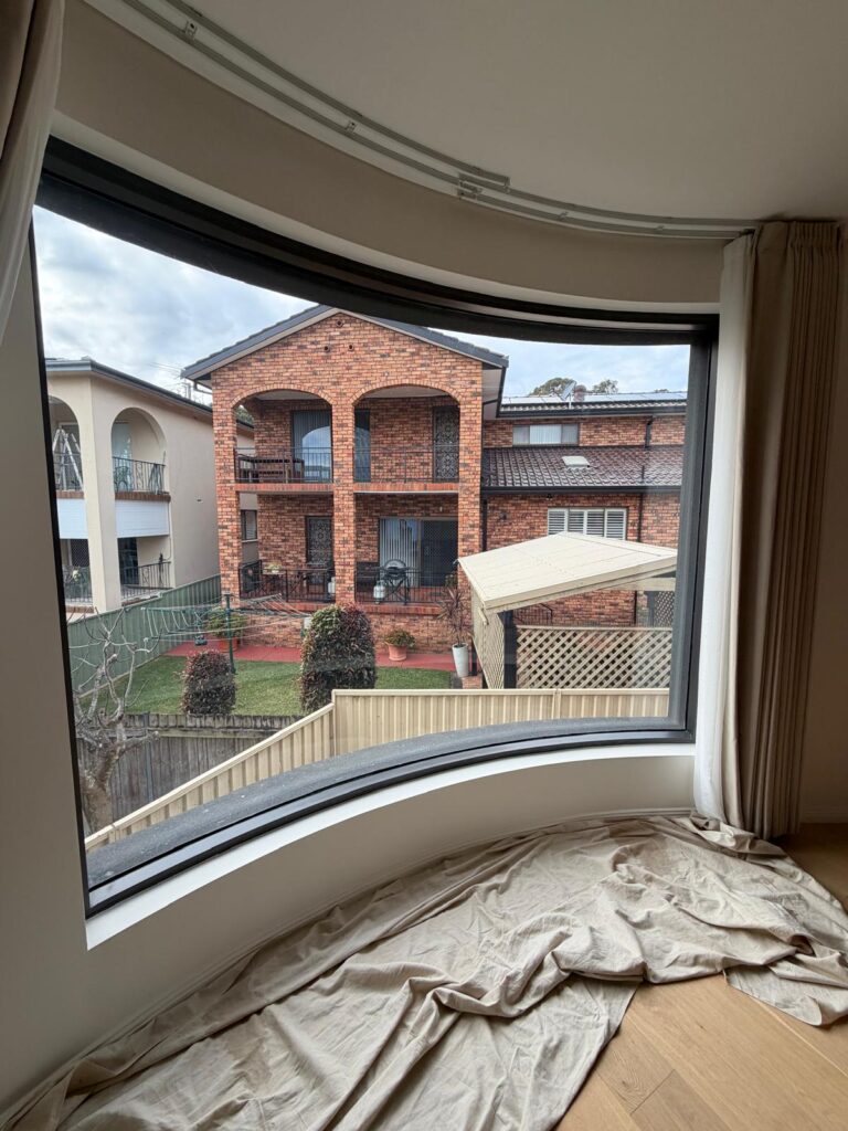 Residential curved window before frosted film installation